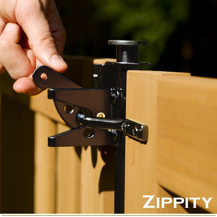 Hand opening black metal gate latch installed on a wooden fence panel outdoors