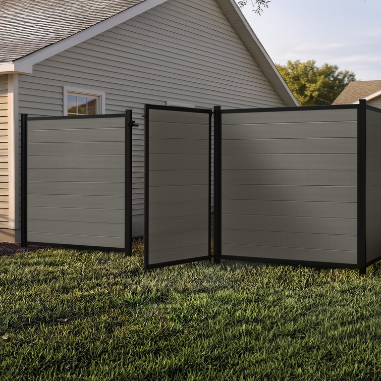 6 ft tall composite privacy fence with slate gray composite boards, black aluminum frame, and matching walk gate installed in a residential backyard.