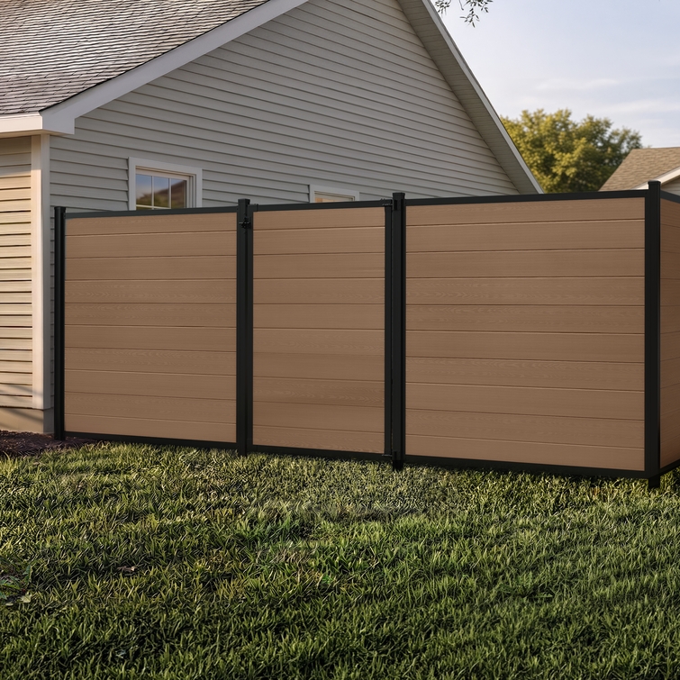 6 ft tall composite privacy fence with walnut brown composite boards, black aluminum frame, and closed matching walk gate in a residential backyard.