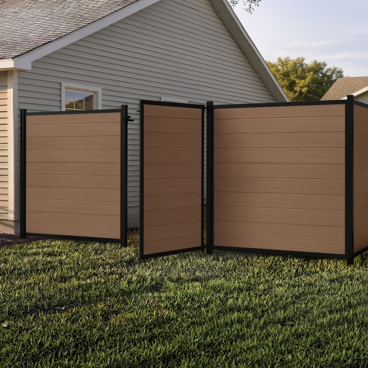 6 ft tall composite privacy fence with walnut brown composite boards, black aluminum frame, and matching walk gate installed in a residential backyard.