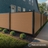 angled view of walnut brown composite privacy fence panels forming a continuous backyard fence line