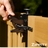 Hand opening black metal gate latch installed on a wooden fence panel outdoors