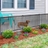 Black metal no-dig fence installed along house with small dog safely enclosed in landscaped yard