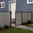 4 ft tall composite privacy fence with slate gray composite boards, black aluminum frame, and matching walk gate installed in a residential backyard.