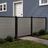 4 ft tall composite privacy fence with slate gray composite boards, black aluminum frame, and closed matching walk gate in a residential backyard.