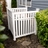 White vinyl AC unit enclosure fence with decorative picket-style panels installed beside home exterior